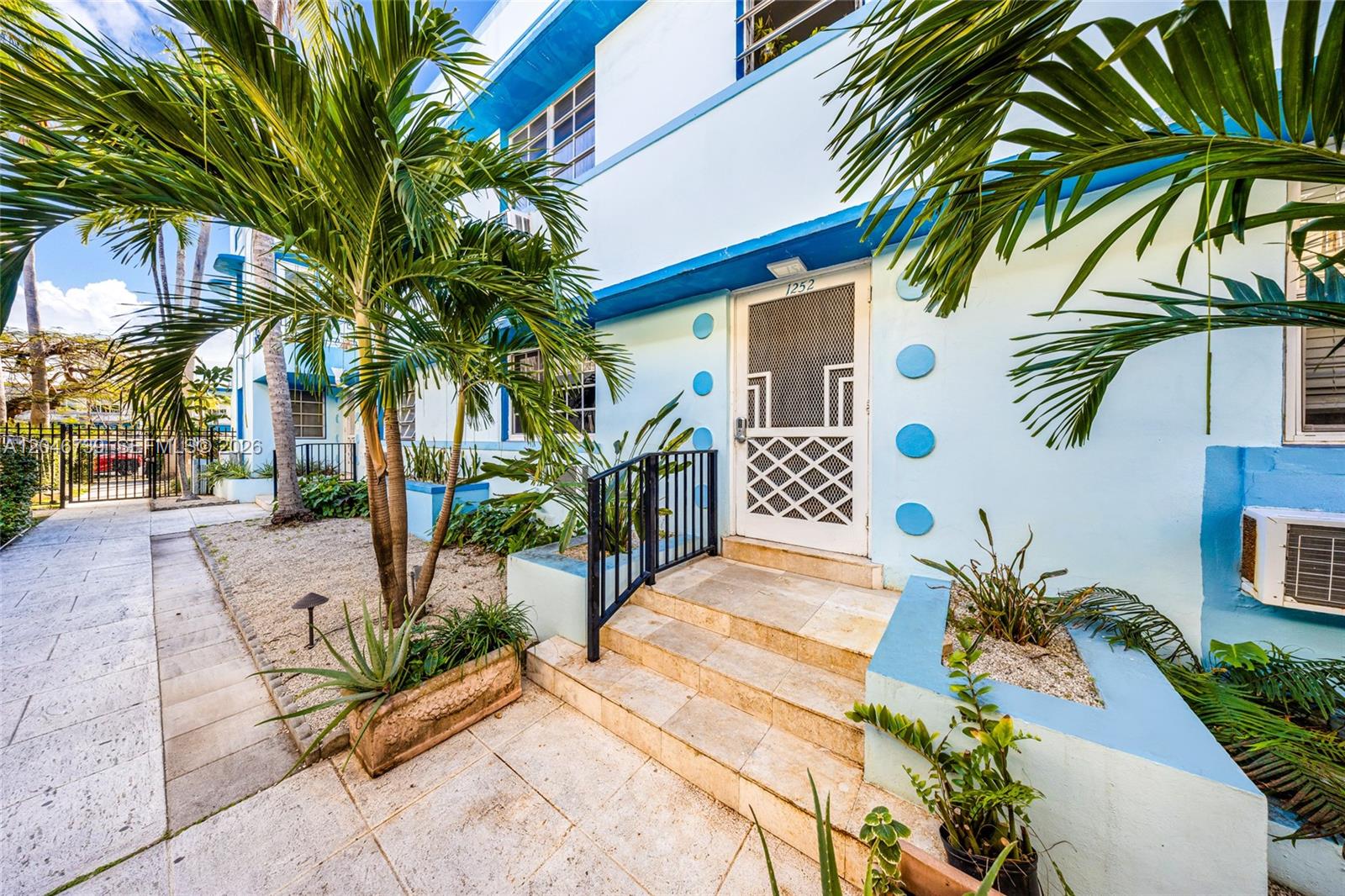 The exterior of a light blue building features a white screen door and stone steps — 1250 Drexel Ave # 8, Miami Beach FL 33139, MIAMI BEACH, FL