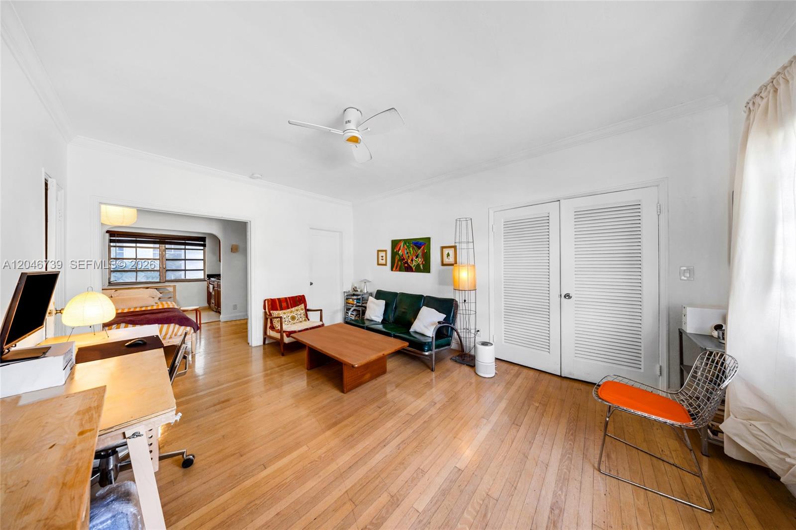 A living room with hardwood floors, a dark green sofa, and an adjacent bedroom area — 1250 Drexel Ave # 8, Miami Beach FL 33139, MIAMI BEACH, FL