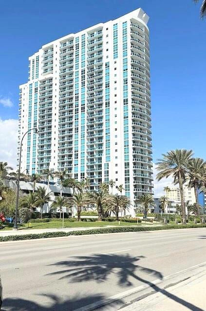 A tall, modern white residential high-rise building stands against a clear blue sky — 1945 S Ocean Drive # 701, Hallandale Beach FL 33009, HALLANDALE BEACH, FL