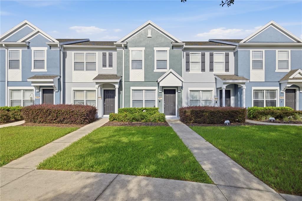 A row of blue and gray multi-story townhomes with front walkways and manicured landscaping — 4471 SW 49TH AVENUE, OCALA, FL
