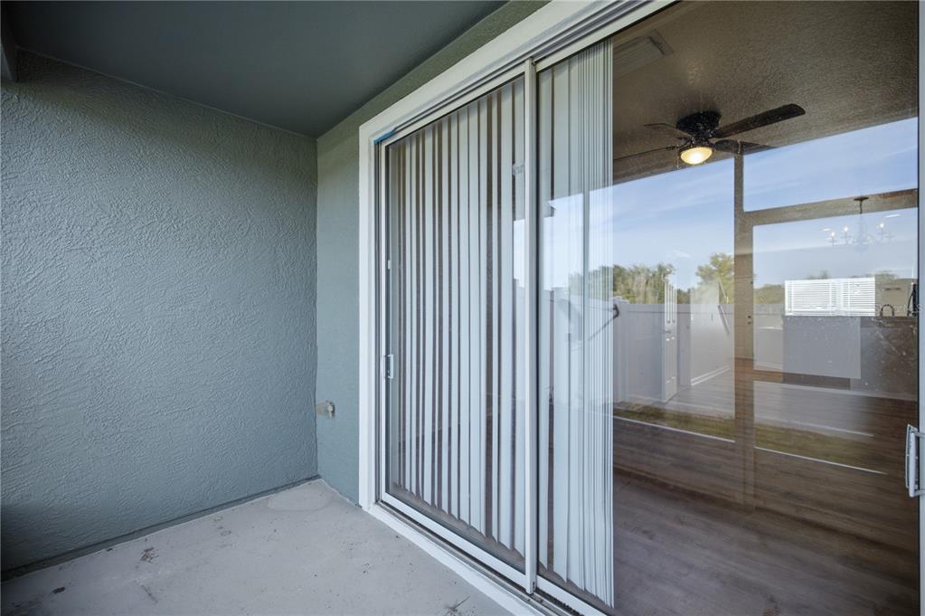 A covered patio with a textured gray wall and a sliding glass door — 4471 SW 49TH AVENUE, OCALA, FL