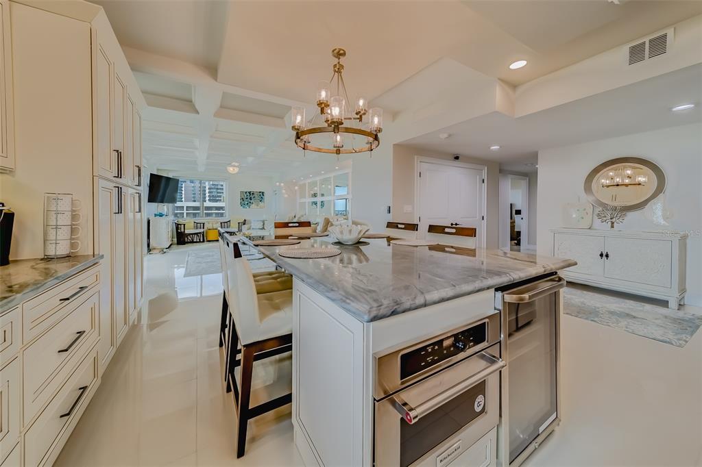 A modern kitchen features a marble-topped island with built-in appliances and white cabinetry — 1460 GULF BOULEVARD UNIT 1210, CLEARWATER BEACH, FL