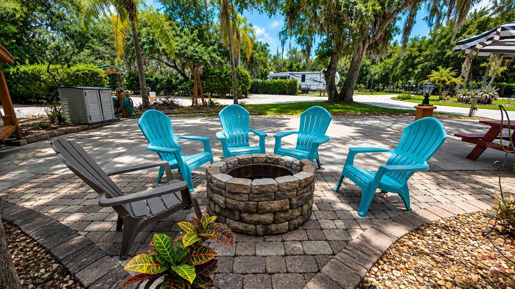 A stone fire pit is surrounded by four chairs on a paved patio outdoors — 243 SADDLE LANE, RIVER RANCH, FL