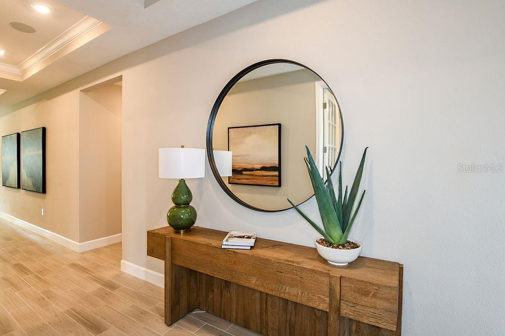 A wooden console table sits against a wall beneath a large round mirror — 5 ARMENIA COURT, PALM COAST, FL