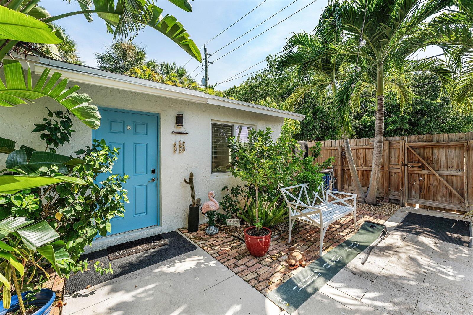 A white exterior building with a blue door, patio, and tropical landscaping — 334 NE 7th Avenue, Delray Beach FL 33483, DELRAY BEACH, FL