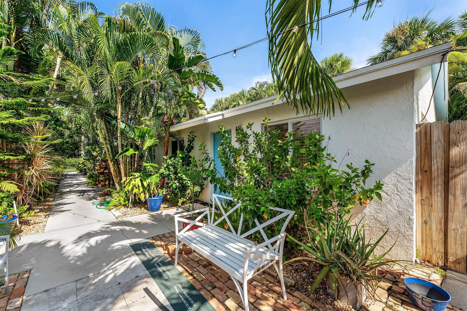 A white bench sits on a brick patio in front of a small white building — 334 NE 7th Avenue, Delray Beach FL 33483, DELRAY BEACH, FL