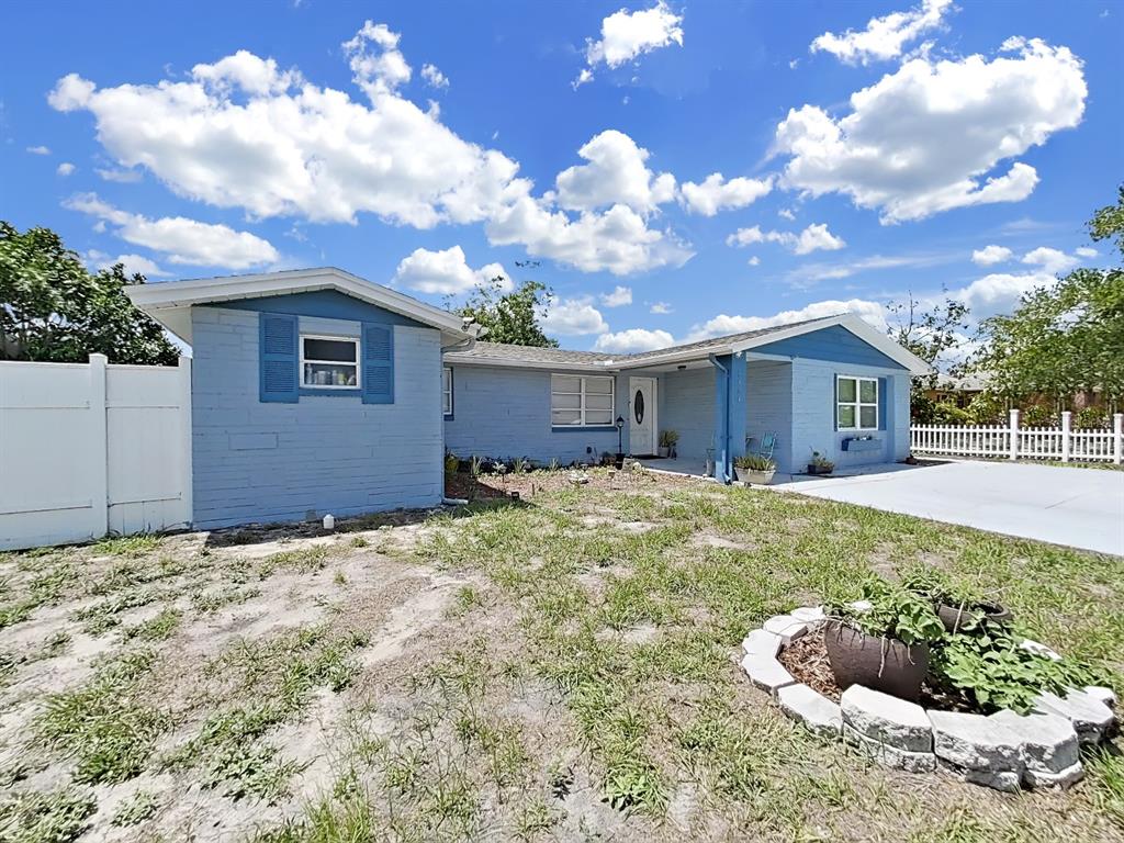 A light blue single-story house with a white fence and a stone-bordered planter — 3424 TRUMAN DRIVE, HOLIDAY, FL