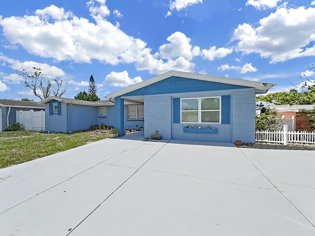 A light blue single-story house with a white fence and a large concrete driveway — 3424 TRUMAN DRIVE, HOLIDAY, FL