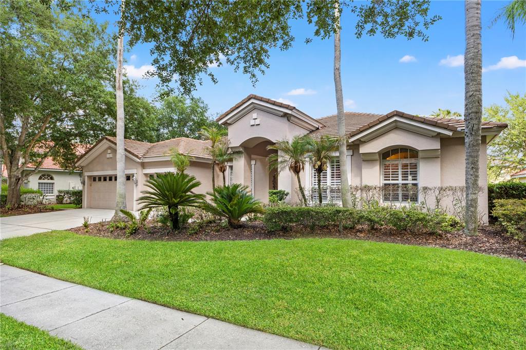 A single-story house with a beige stucco exterior, a tiled roof, and a manicured lawn — 17861 ARBOR GREENE DRIVE, TAMPA, FL