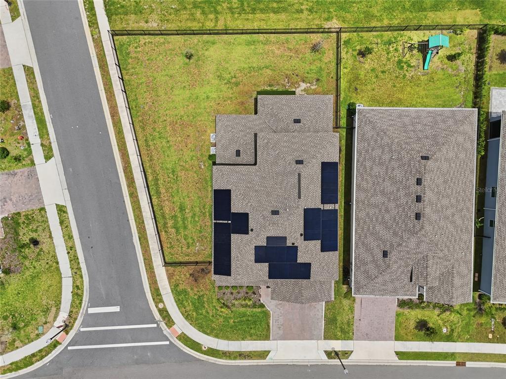 An aerial view shows a house with solar panels on its roof and a fenced yard — 4217 EASTMINSTER ROAD, DAVENPORT, FL