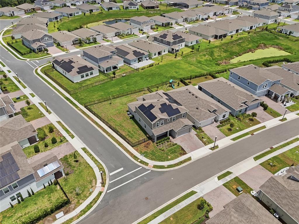 An aerial view shows suburban houses with solar panels and fenced yards along paved streets — 4217 EASTMINSTER ROAD, DAVENPORT, FL