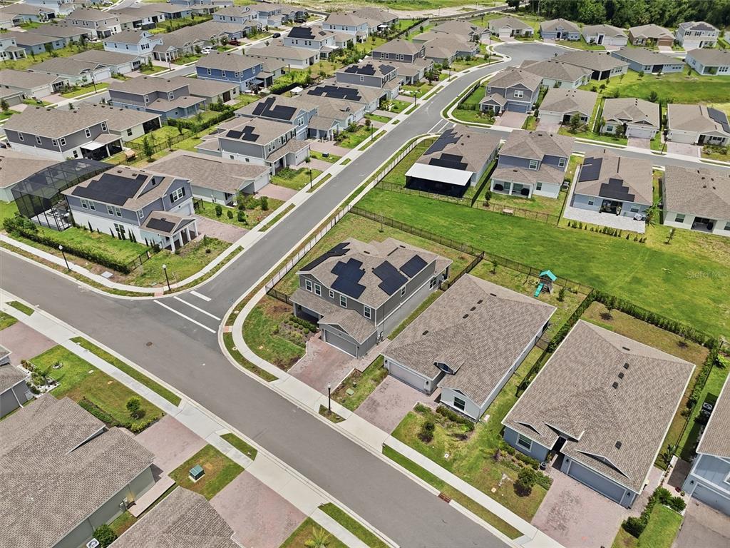 An aerial view shows a suburban neighborhood with many houses featuring rooftop solar panels — 4217 EASTMINSTER ROAD, DAVENPORT, FL
