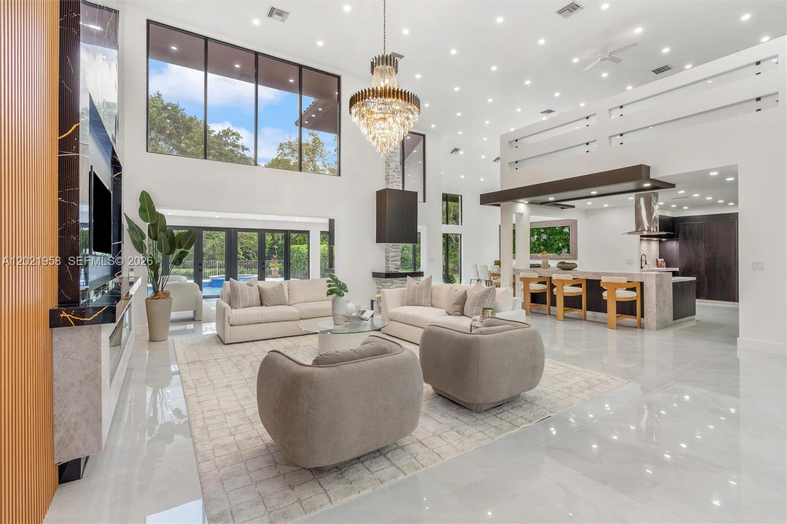 A spacious, modern open-concept living room features high ceilings, a large chandelier, and marble flooring — 7011 Hialeah Ln, Parkland FL 33067, PARKLAND, FL
