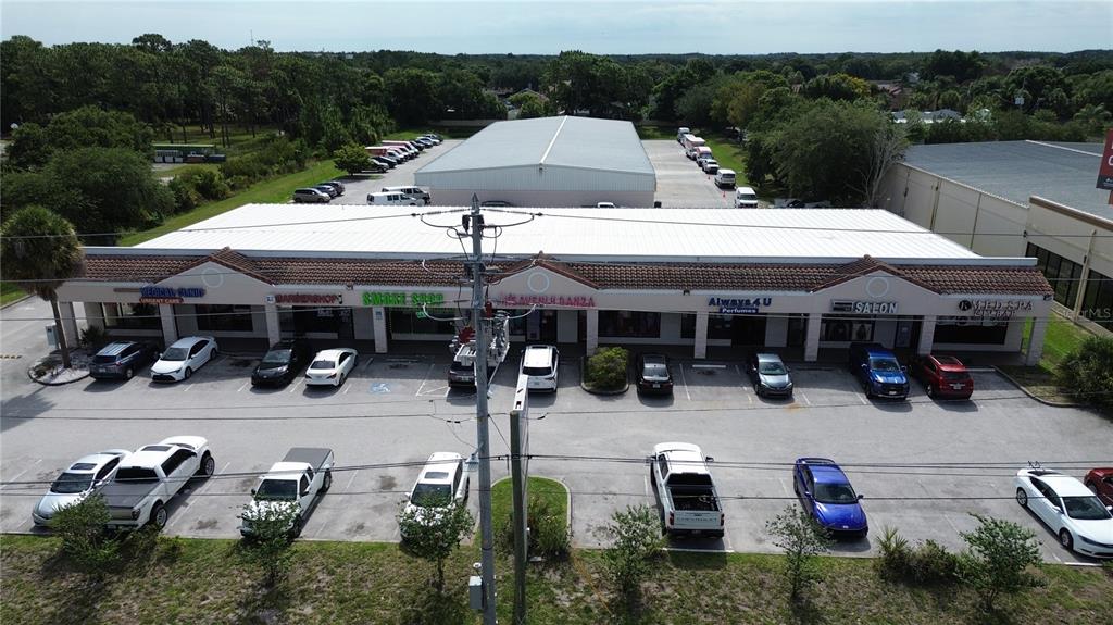 An aerial view shows a single-story commercial strip mall with a parking lot in front — 11601 S ORANGE BLOSSOM TRAIL UNIT 108, ORLANDO, FL