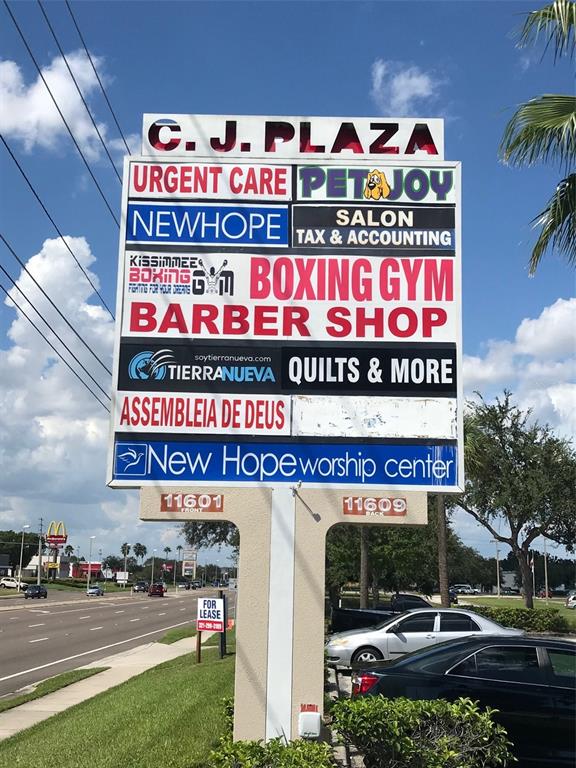 A large multi-tenant sign stands in front of a commercial plaza under a blue sky — 11601 S ORANGE BLOSSOM TRAIL UNIT 108, ORLANDO, FL