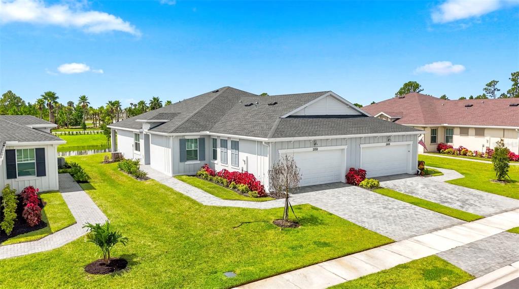 An exterior view of a duplex house with grey siding, shingled roofs, and paved driveways — 2286 CERULEAN DRIVE NW, PALM BAY, FL
