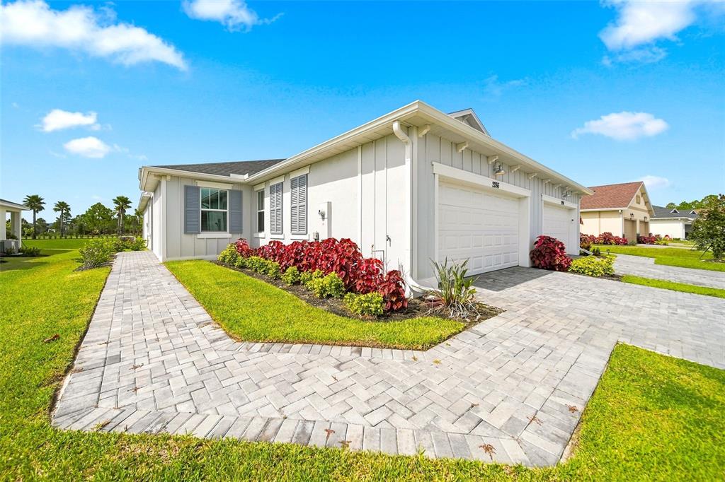 A light-colored house with a two-car garage and a paved walkway on a sunny day — 2286 CERULEAN DRIVE NW, PALM BAY, FL