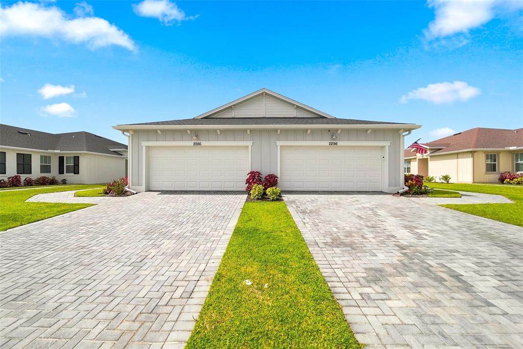 A duplex house exterior features two garage doors, a paved driveway, and a grassy lawn — 2286 CERULEAN DRIVE NW, PALM BAY, FL