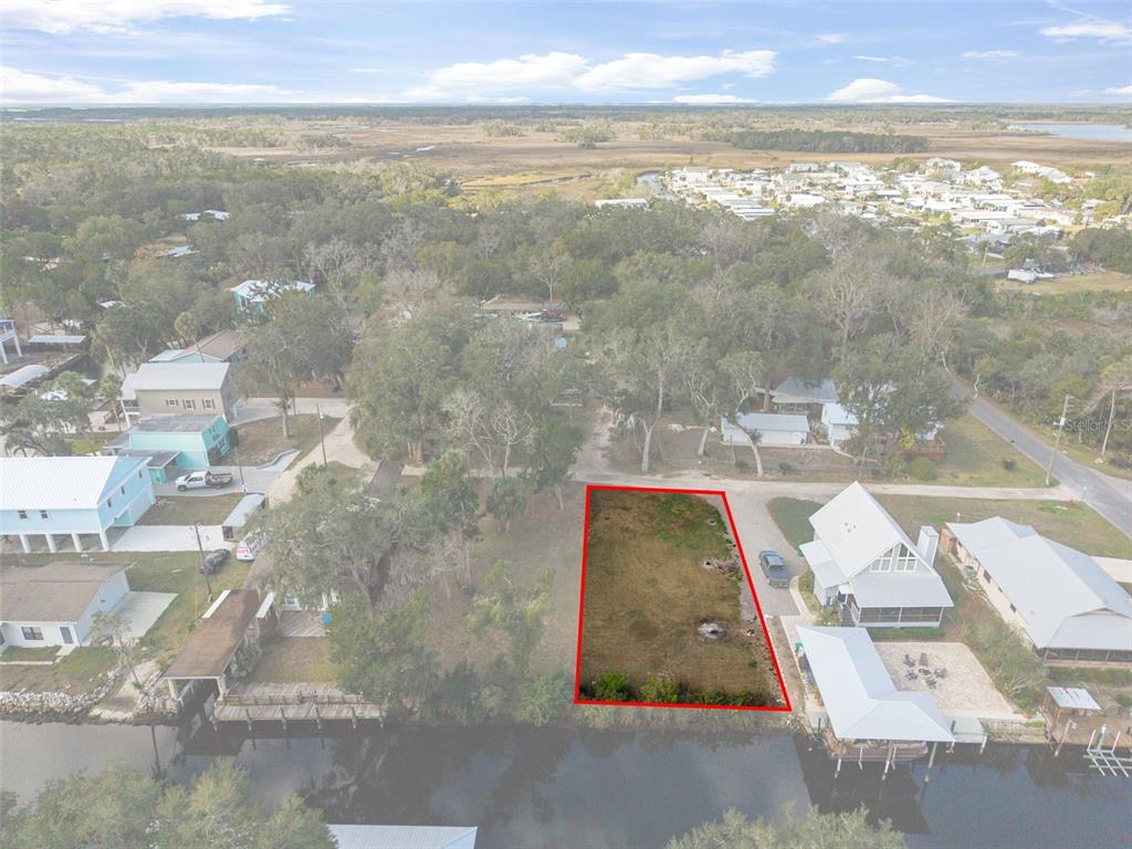 An aerial view shows a vacant waterfront lot outlined in red next to existing houses — 5787 S KINGDOM TERRACE, HOMOSASSA, FL