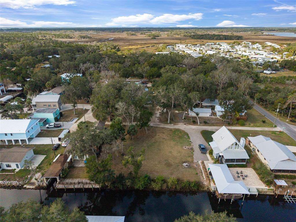 An aerial view shows waterfront houses with docks along a canal near a wooded area — 5787 S KINGDOM TERRACE, HOMOSASSA, FL