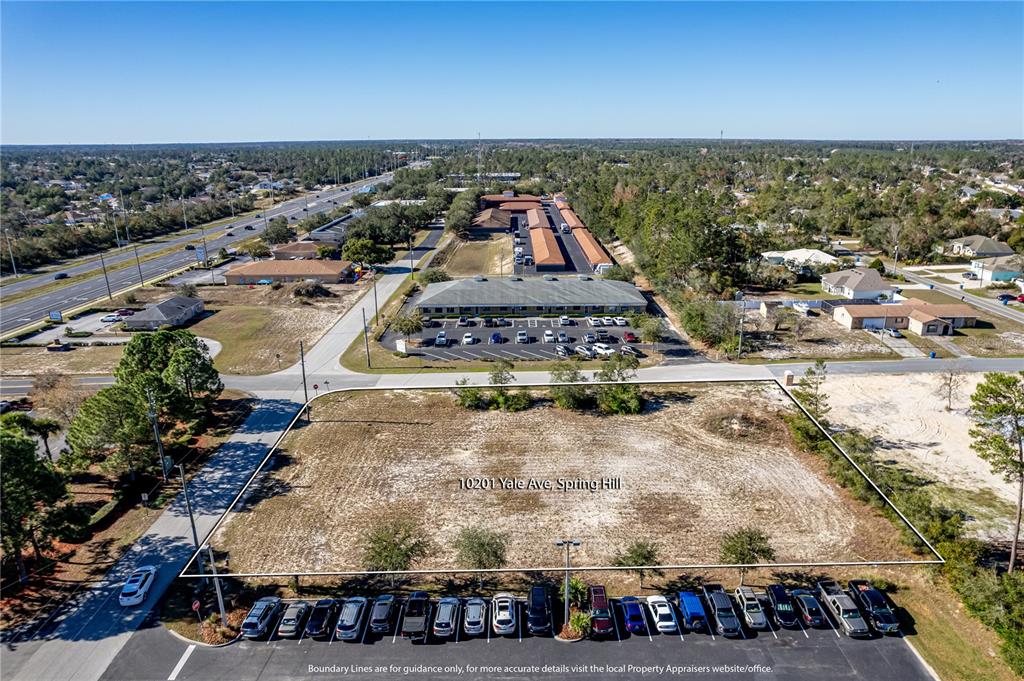 An aerial view shows a vacant, rectangular lot bordered by a parking area and roads — 10201 YALE AVENUE, WEEKI WACHEE, FL