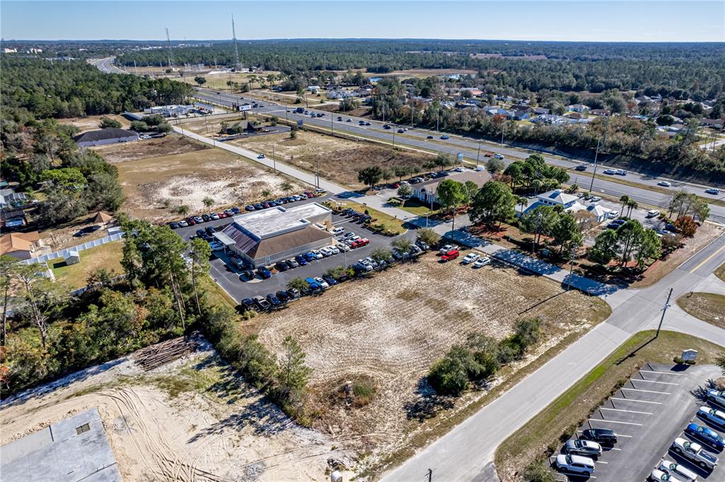 An aerial view shows a commercial building with a parking lot next to vacant land — 10201 YALE AVENUE, WEEKI WACHEE, FL