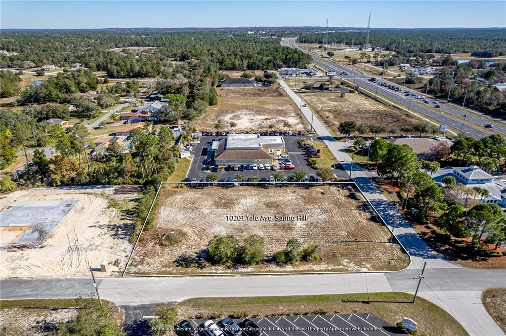 An aerial view shows a vacant rectangular lot adjacent to a commercial building and road — 10201 YALE AVENUE, WEEKI WACHEE, FL