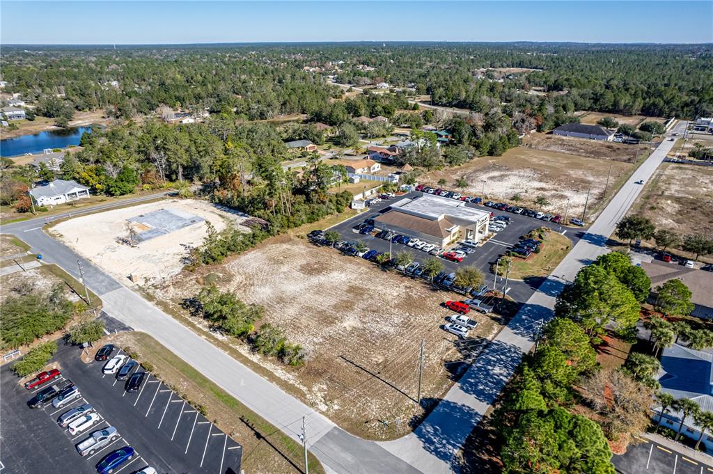An aerial view shows a commercial building with a parking lot and adjacent vacant land — 10201 YALE AVENUE, WEEKI WACHEE, FL