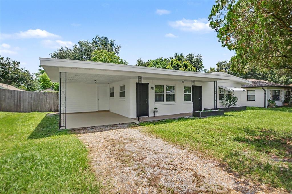A white single-story house with a gravel driveway, a carport, and two black front doors — 4965 ORANGE AVENUE, WINTER PARK, FL