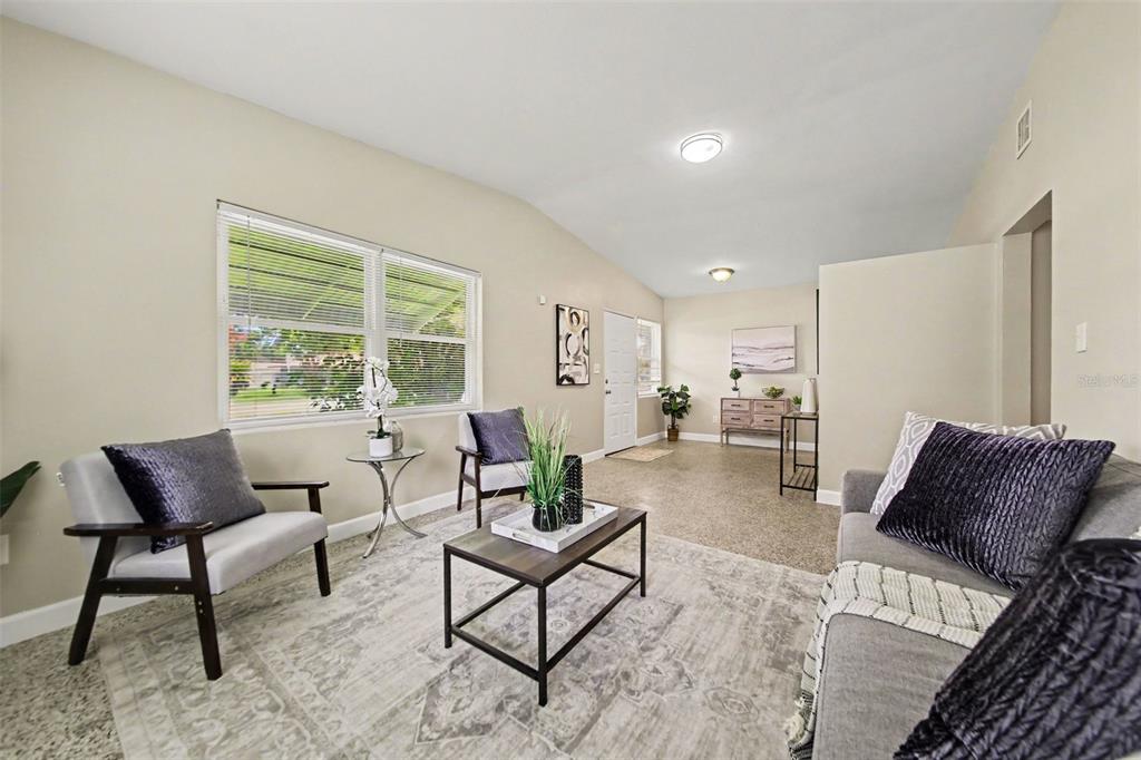 A living room features light walls, a patterned area rug, and modern gray furniture — 4965 ORANGE AVENUE, WINTER PARK, FL