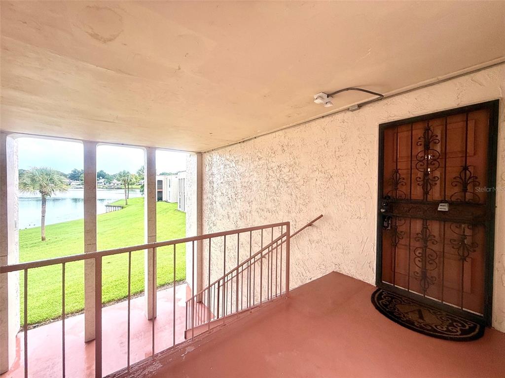 An outdoor apartment balcony features a metal security door, a railing, and a lake view — 534 ORANGE DRIVE UNIT 27, ALTAMONTE SPRINGS, FL