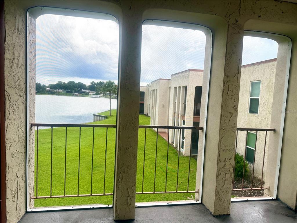 A screened-in balcony overlooks a grassy lawn and a lake next to apartment buildings — 534 ORANGE DRIVE UNIT 27, ALTAMONTE SPRINGS, FL