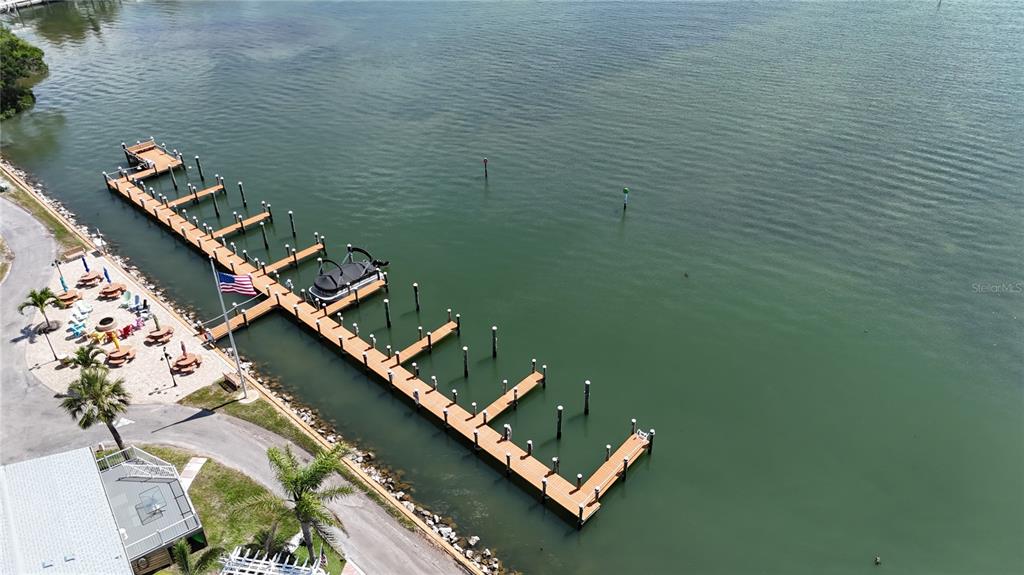 An aerial view shows a wooden boat dock extending into a calm body of water — 2601 GULF DRIVE N UNIT 310, BRADENTON BEACH, FL