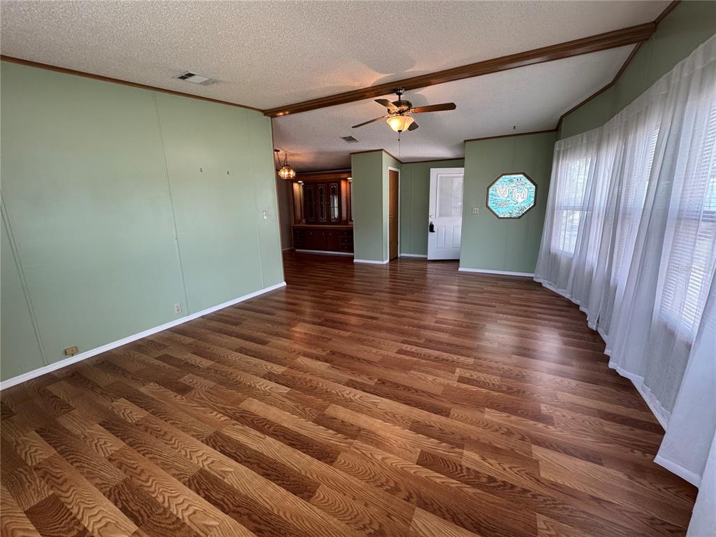 A living room with green walls, wood-look flooring, a ceiling fan, and a stained-glass window — 5310 TIGERS TAIL, LEESBURG, FL