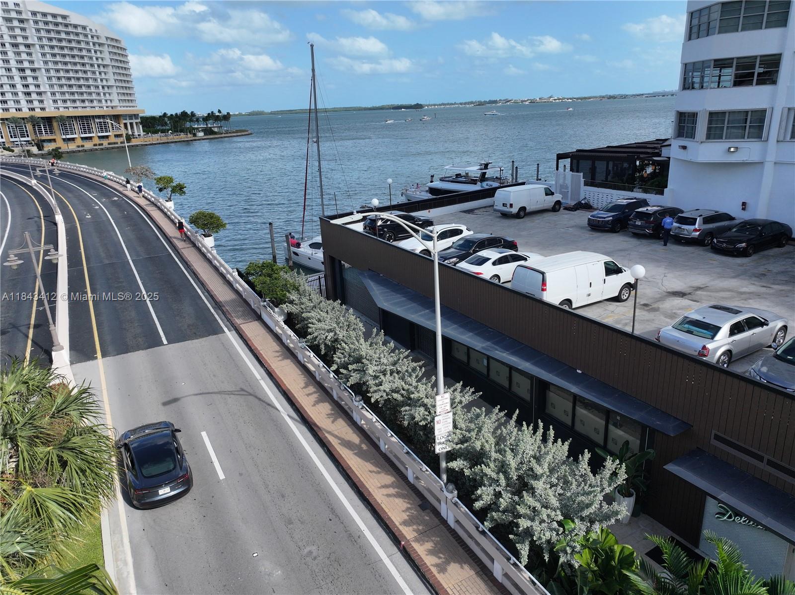 An elevated view shows a road, a parking lot with several vehicles, and a waterfront — 801 Brickell Bay Dr, Miami FL 33131, MIAMI, FL