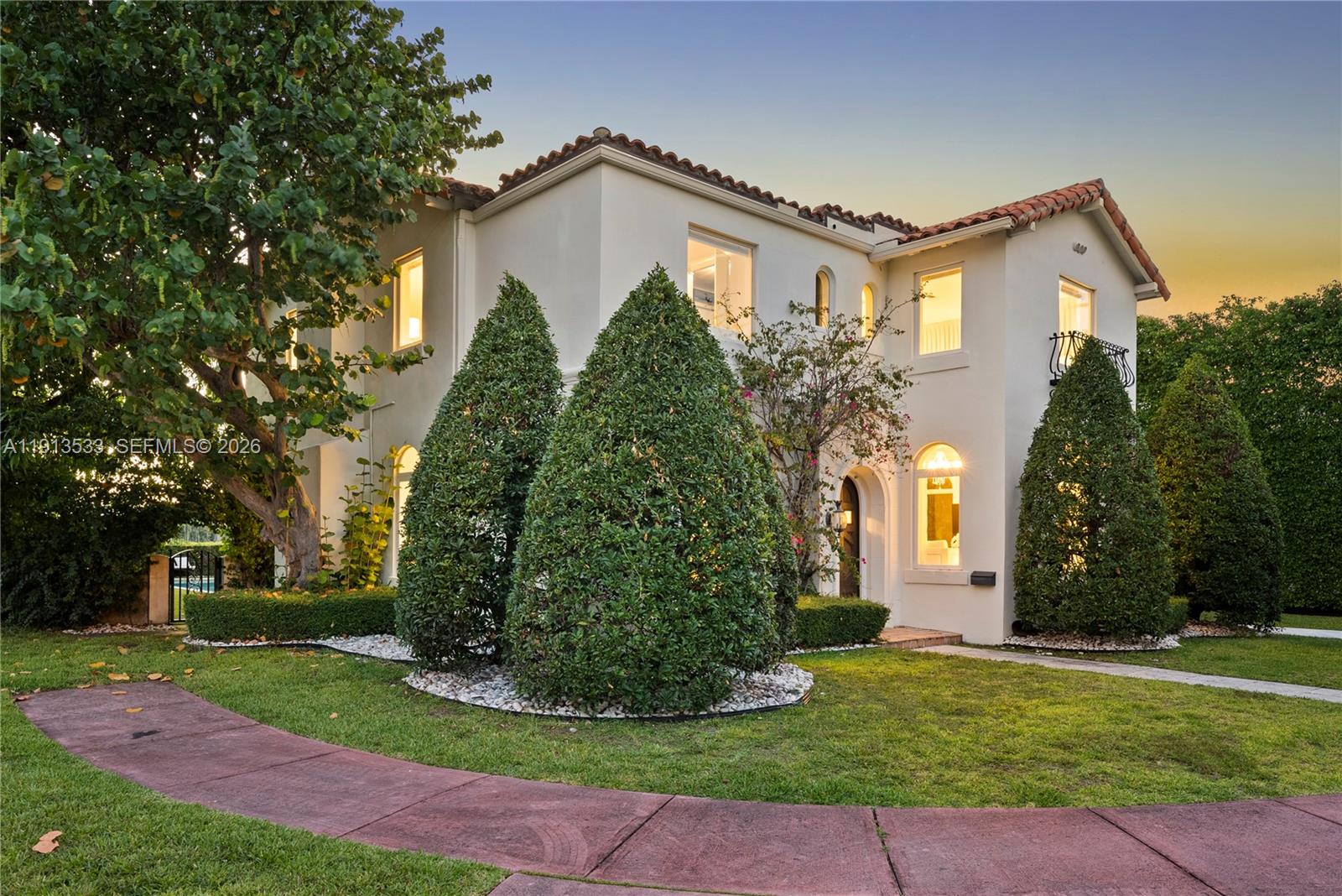 A two-story stucco house features a red tile roof, arched windows, and manicured landscaping — 5800 La Gorce Dr, Miami Beach FL 33140, MIAMI BEACH, FL
