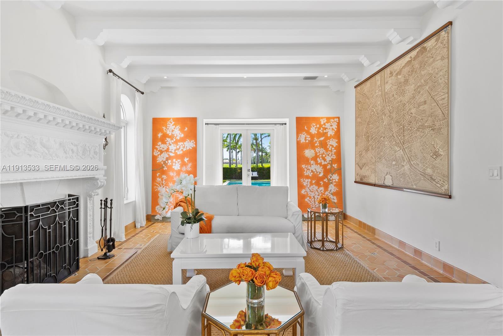 A bright living room features white furniture, a fireplace, orange floral panels, and a large map — 5800 La Gorce Dr, Miami Beach FL 33140, MIAMI BEACH, FL