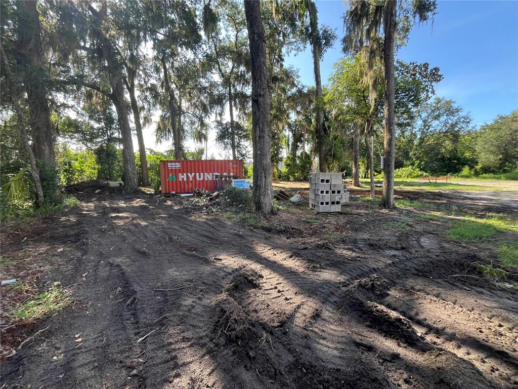 A dirt lot features a red shipping container and a stack of concrete blocks — 1222 NW 2ND STREET, GAINESVILLE, FL