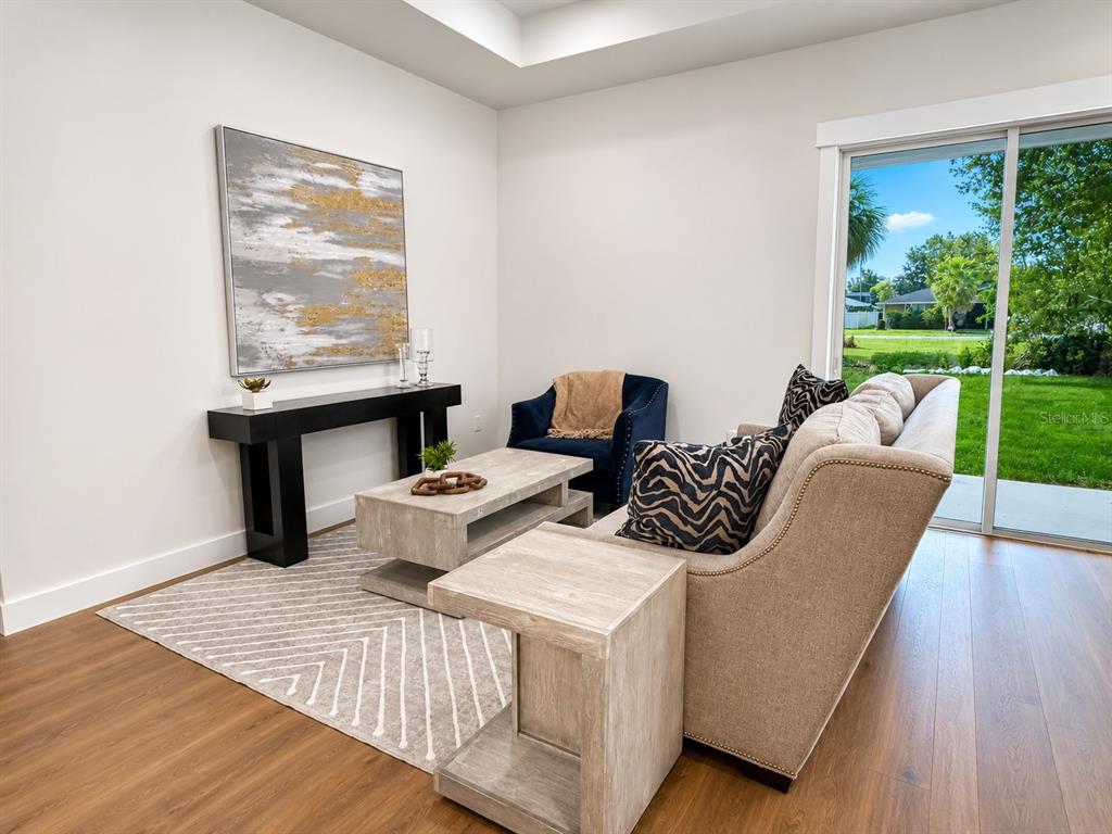 A living room features a beige sofa, a coffee table, and a sliding glass door — 1835 ROOSEVELT AVENUE, SANFORD, FL