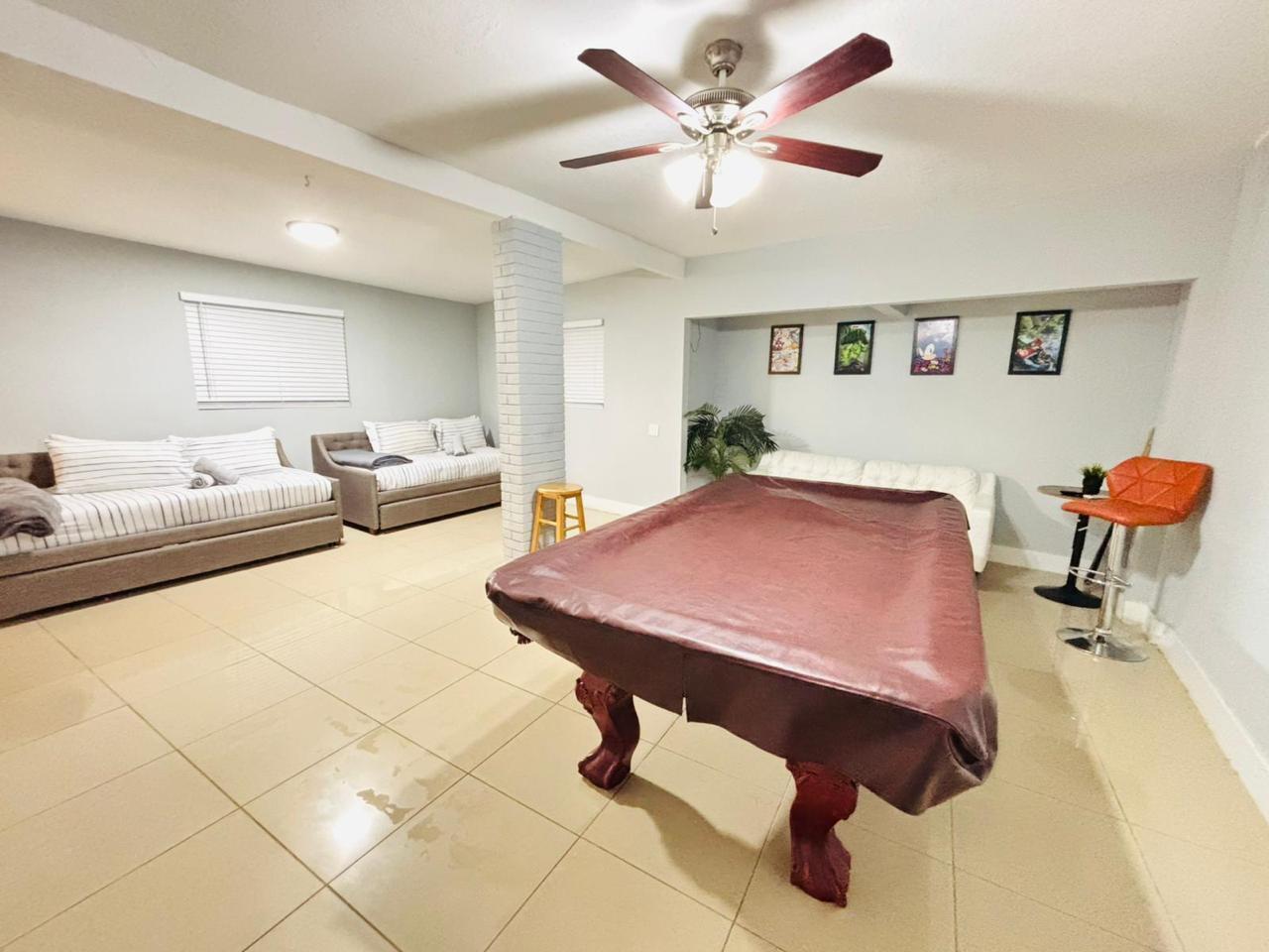 A basement recreation room features a pool table, two daybeds, tile flooring, and a ceiling fan — 2010 NE 1st Avenue, Pompano Beach FL 33060, POMPANO BEACH, FL