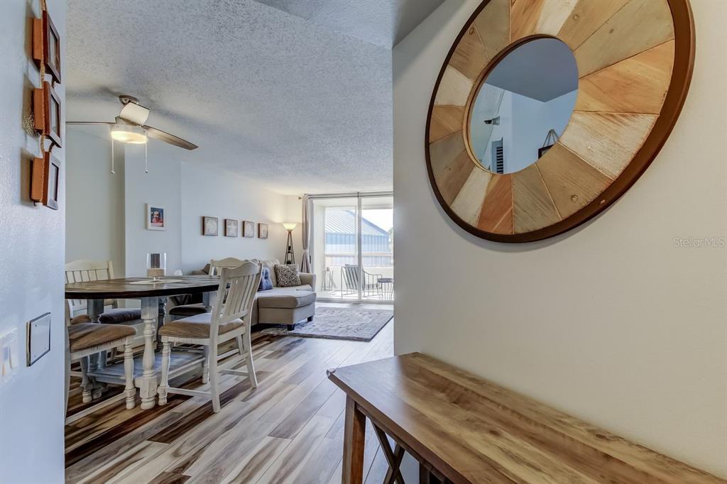 A view from a hallway into a dining area and living room with wood flooring — 2333 FEATHER SOUND DRIVE UNIT B211, CLEARWATER, FL
