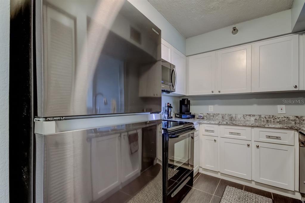 A kitchen features stainless steel appliances, white cabinets, and granite countertops — 2333 FEATHER SOUND DRIVE UNIT B211, CLEARWATER, FL