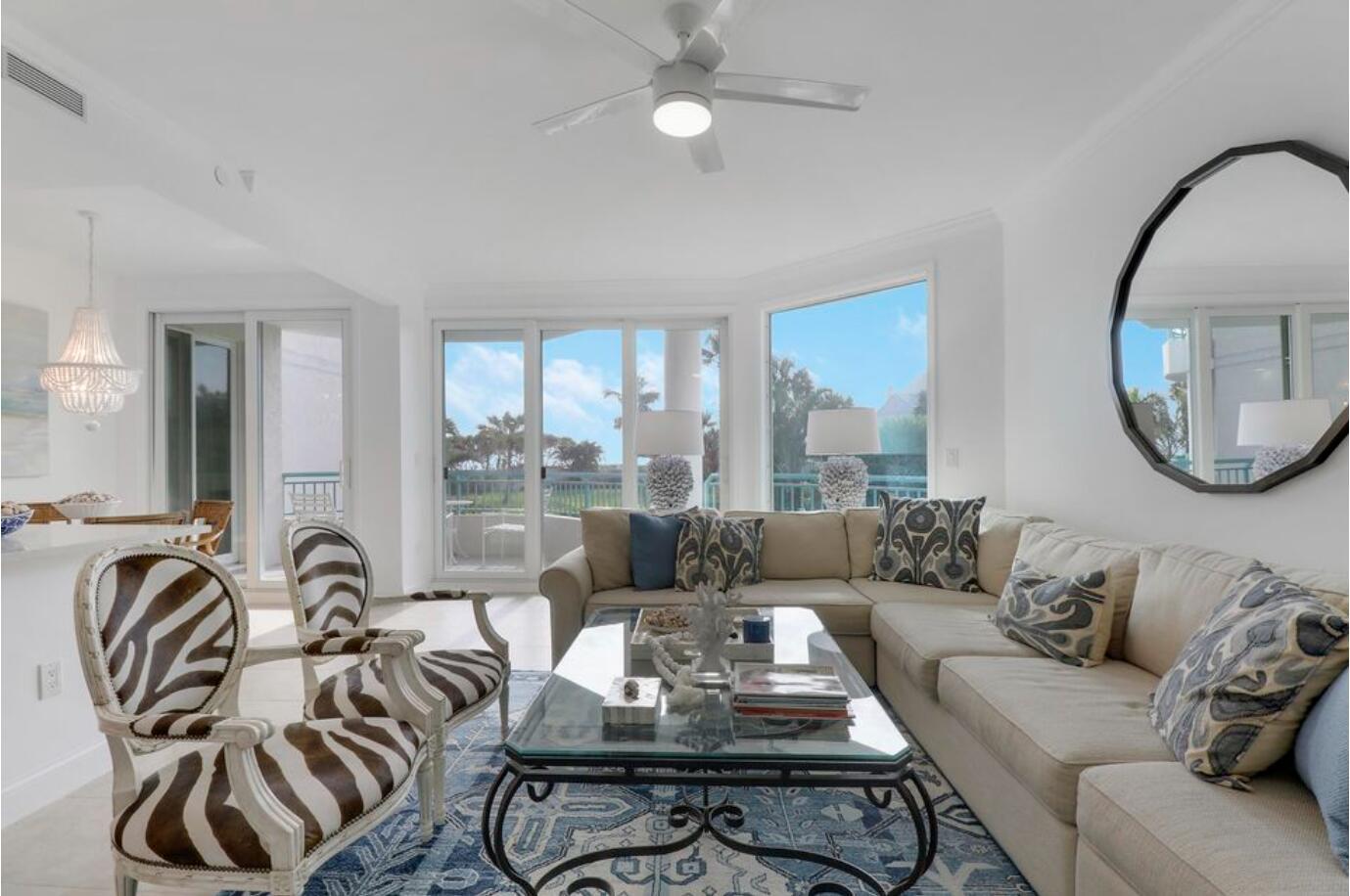 A bright living room features a beige sectional, zebra-print chairs, a glass coffee table, and windows — 2000 S Highway A1a Highway # N104, Jupiter FL 33477, JUPITER, FL