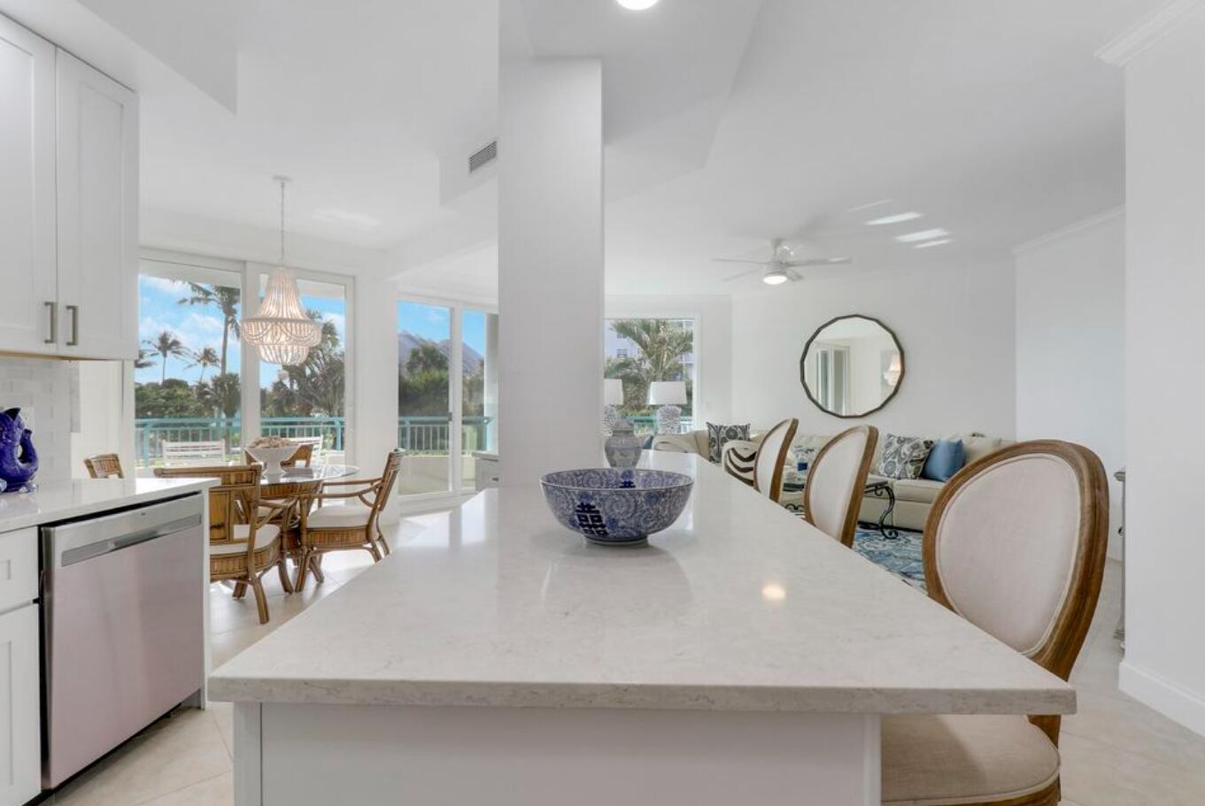 A kitchen island with a blue and white bowl overlooks a dining area and living room — 2000 S Highway A1a Highway # N104, Jupiter FL 33477, JUPITER, FL