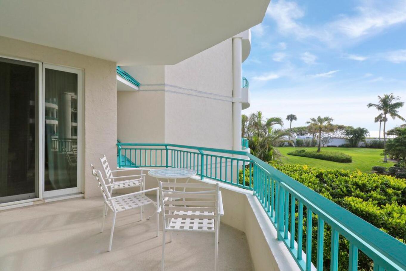 A balcony with white metal furniture overlooks a grassy lawn and palm trees — 2000 S Highway A1a Highway # N104, Jupiter FL 33477, JUPITER, FL