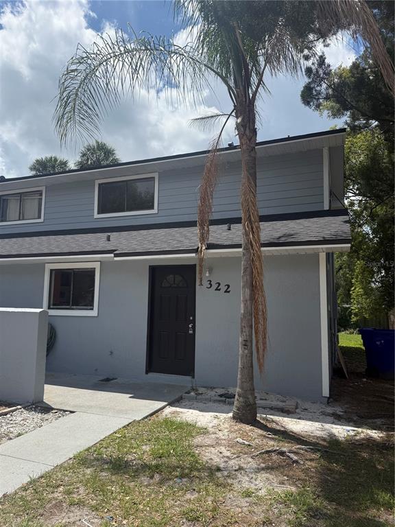 A two-story gray house with a dark front door and a palm tree in front — 1322 VERONA STREET, KISSIMMEE, FL