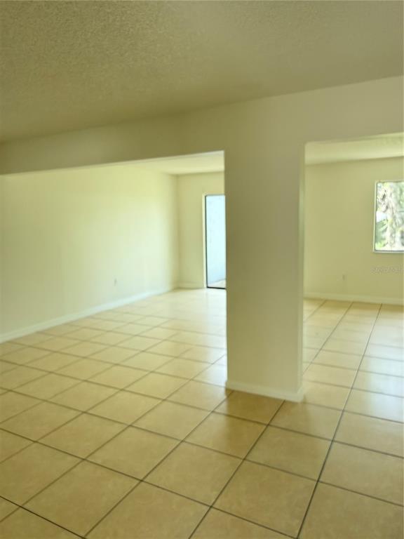 An interior view shows an open-concept living area with light-colored walls and tiled flooring — 1322 VERONA STREET, KISSIMMEE, FL