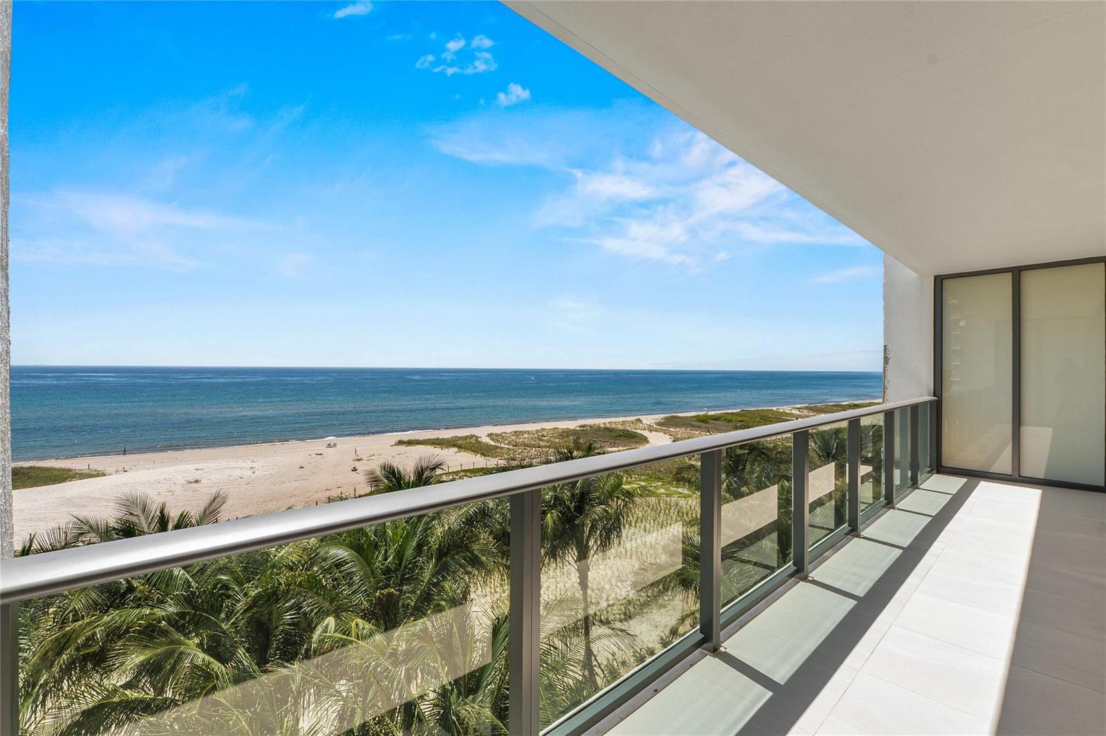A balcony with a glass railing overlooks a sandy beach, palm trees, and the ocean — 900 N Ocean Boulevard # 504, Pompano Beach FL 33062, POMPANO BEACH, FL