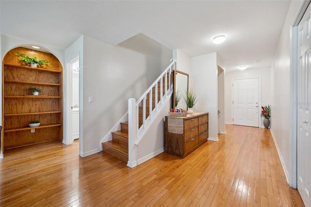 An entryway features hardwood floors, a wooden staircase, a built-in arched bookshelf, and a dresser — 436 OPAL COURT, ALTAMONTE SPRINGS, FL