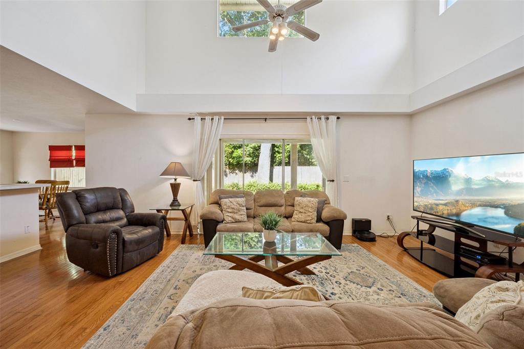 A living room features a high ceiling, hardwood floors, a large television, and sliding doors — 436 OPAL COURT, ALTAMONTE SPRINGS, FL